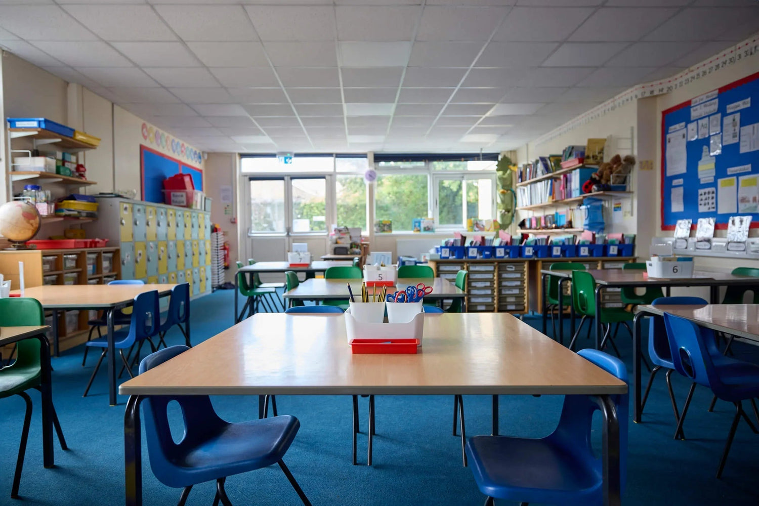 Organized math classroom with student desks, supplies, bookshelves, and storage bins
