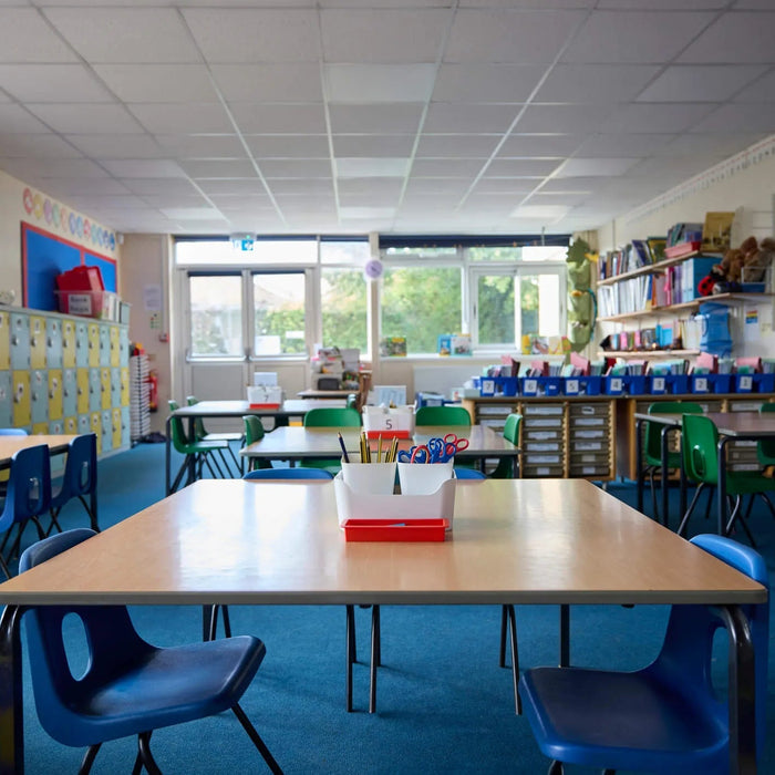 Organized math classroom with student desks, supplies, bookshelves, and storage bins