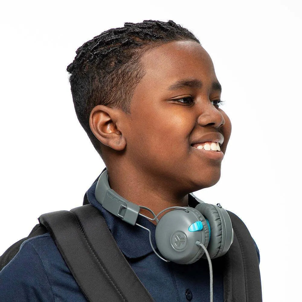 Smiling child wearing backpack and gray JLab JBuddies kids headphones from Underwood Distributing Co.
