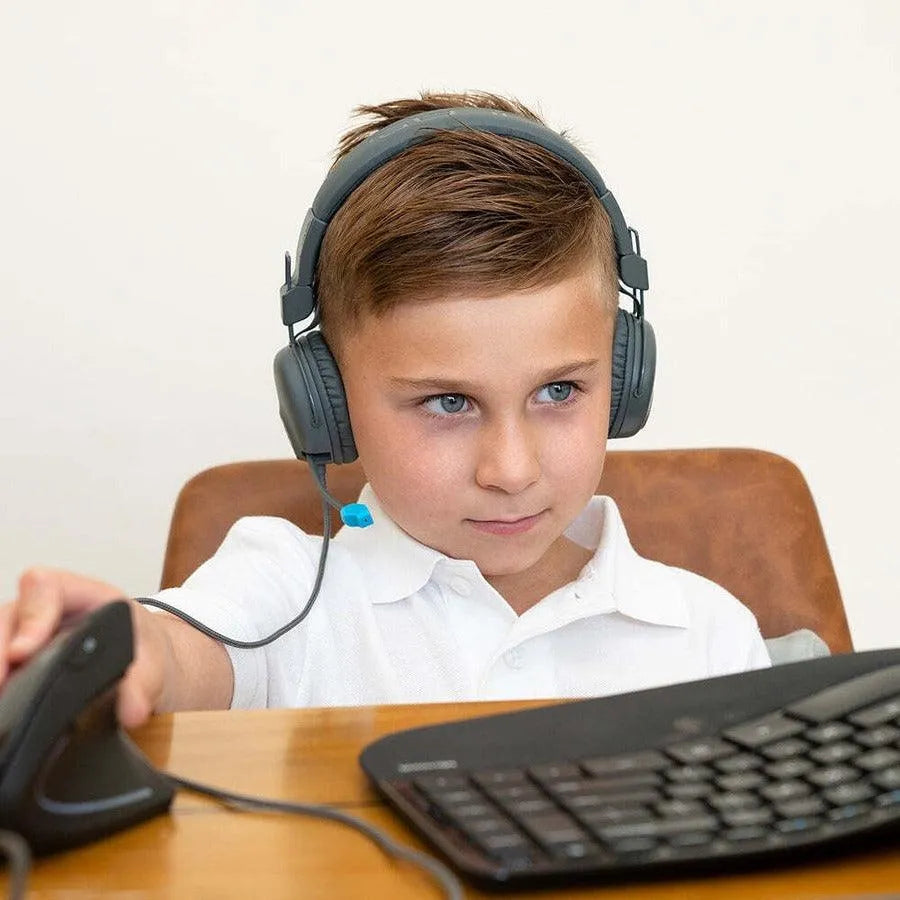 Young boy wearing JLab JBuddies kids headphones using computer at desk, Underwood Distributing Co.