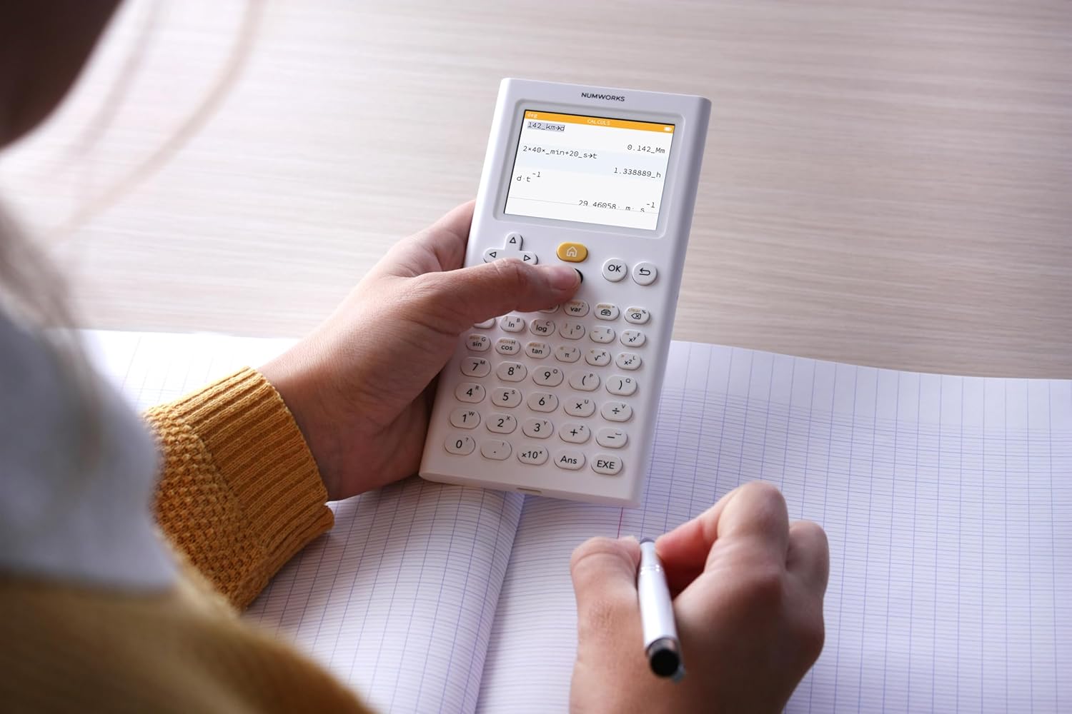 Student using NumWorks graphing calculator on graph paper, education supplies from Underwood Distributing Co.