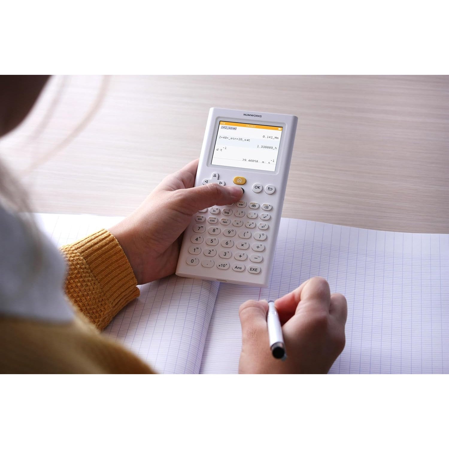 Student using NumWorks graphing calculator on graph paper, education supplies from Underwood Distributing Co.
