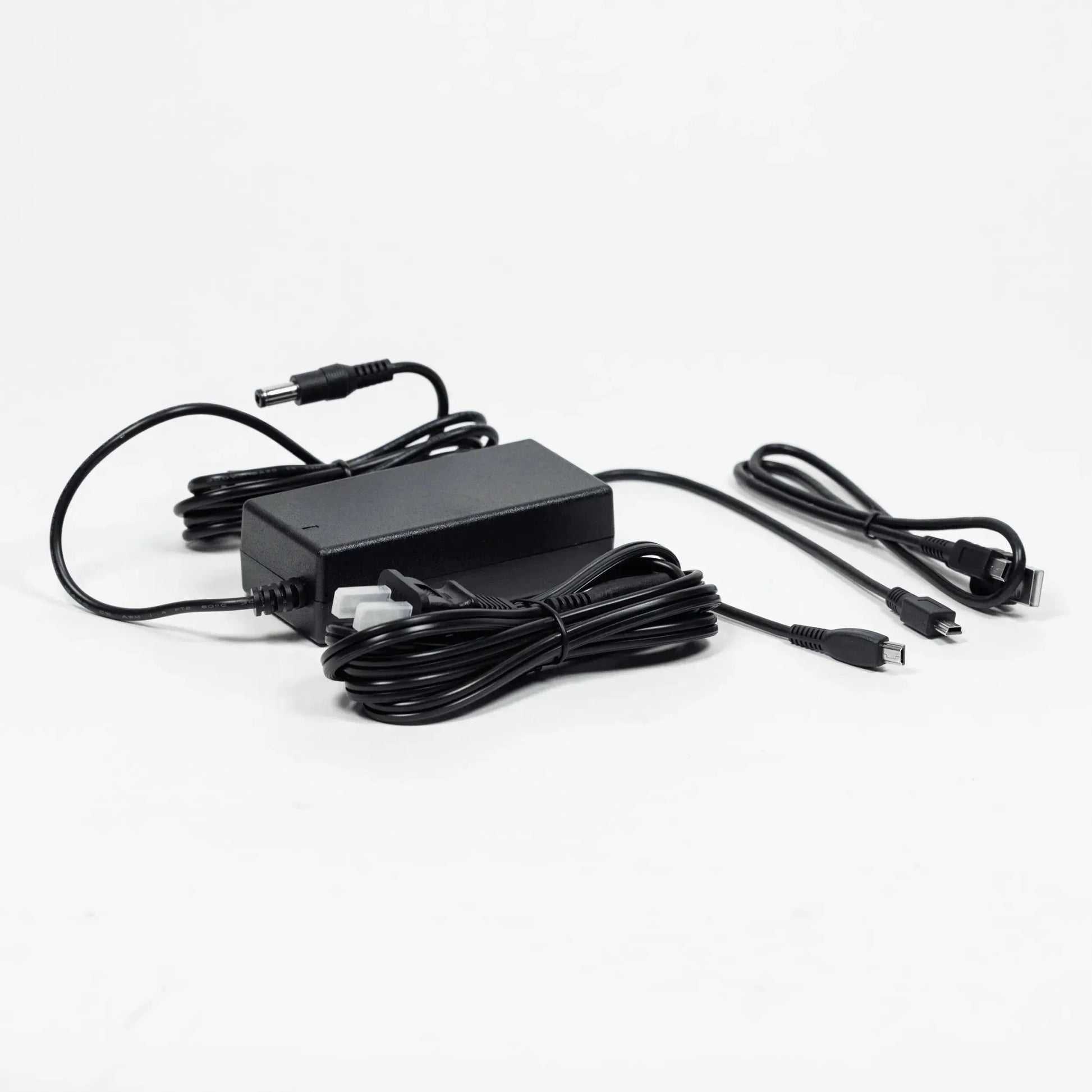 Texas Instruments black power adapter and charging cables set on white background