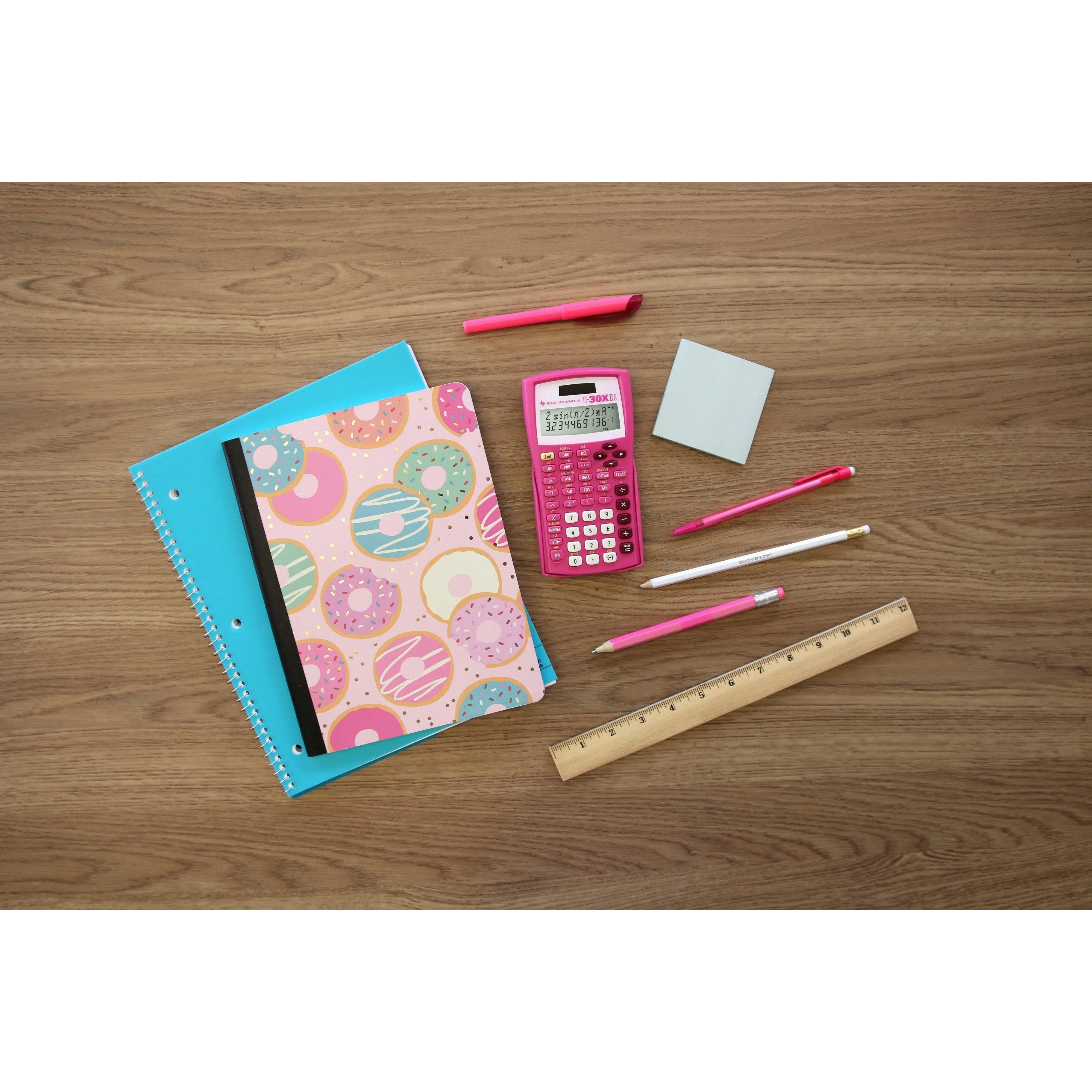 Pink TI-30XIIS scientific calculator on desk with notebooks, ruler, pens, and pencils
