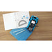 Texas Instruments graphing calculator in robot kit with graph paper, pencils, protractor, and clips on wooden desk.