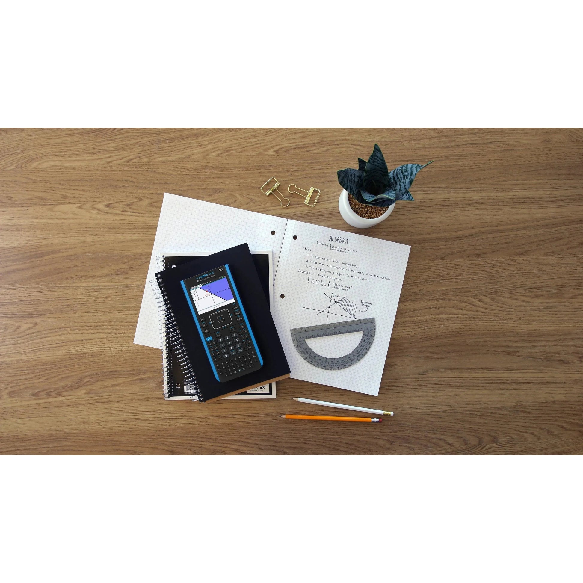 TI-Nspire CX II CAS graphing calculator on desk with math notes, ruler, pencils, and notebooks