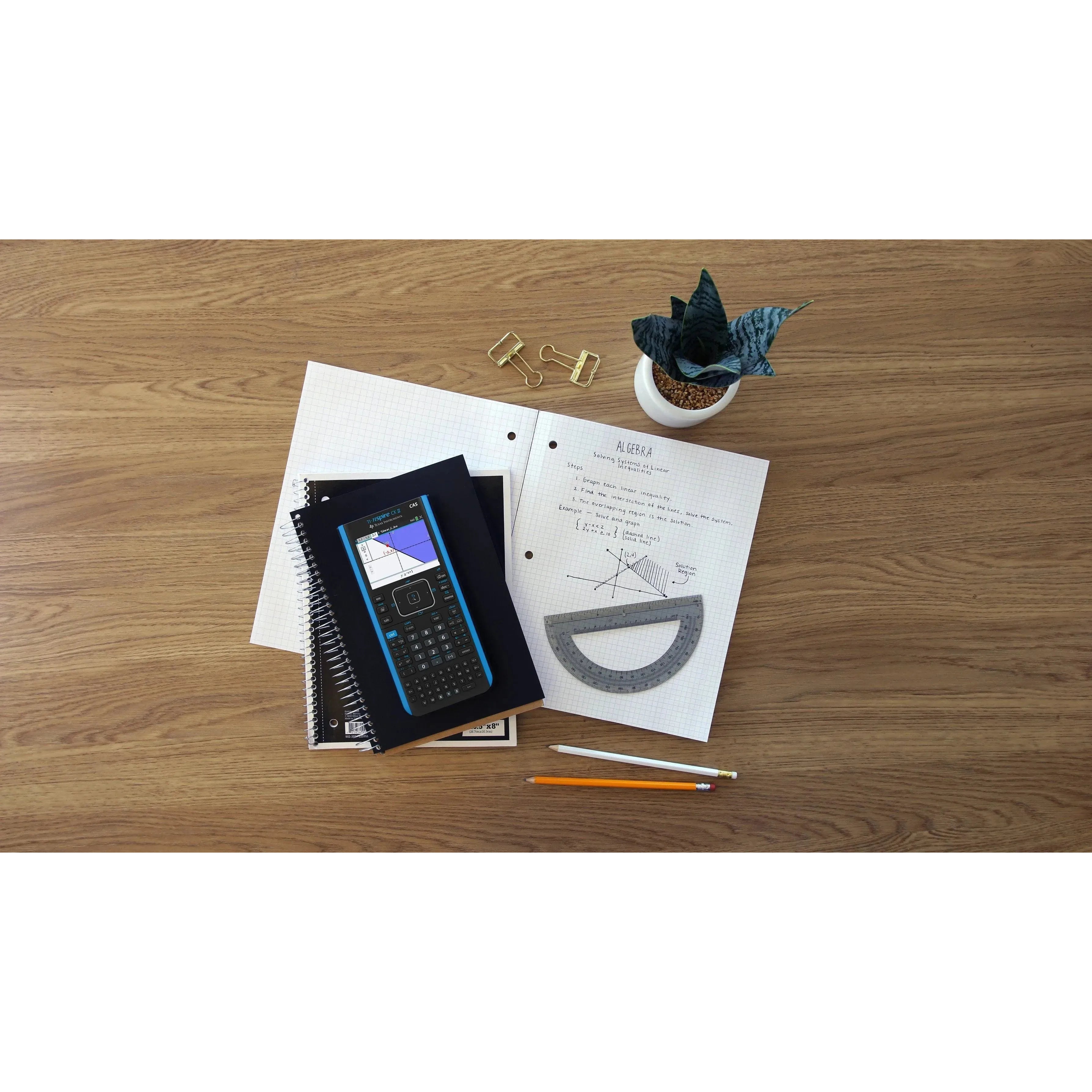 TI-Nspire CX II CAS graphing calculator on desk with math notes, ruler, pencils, and notebooks