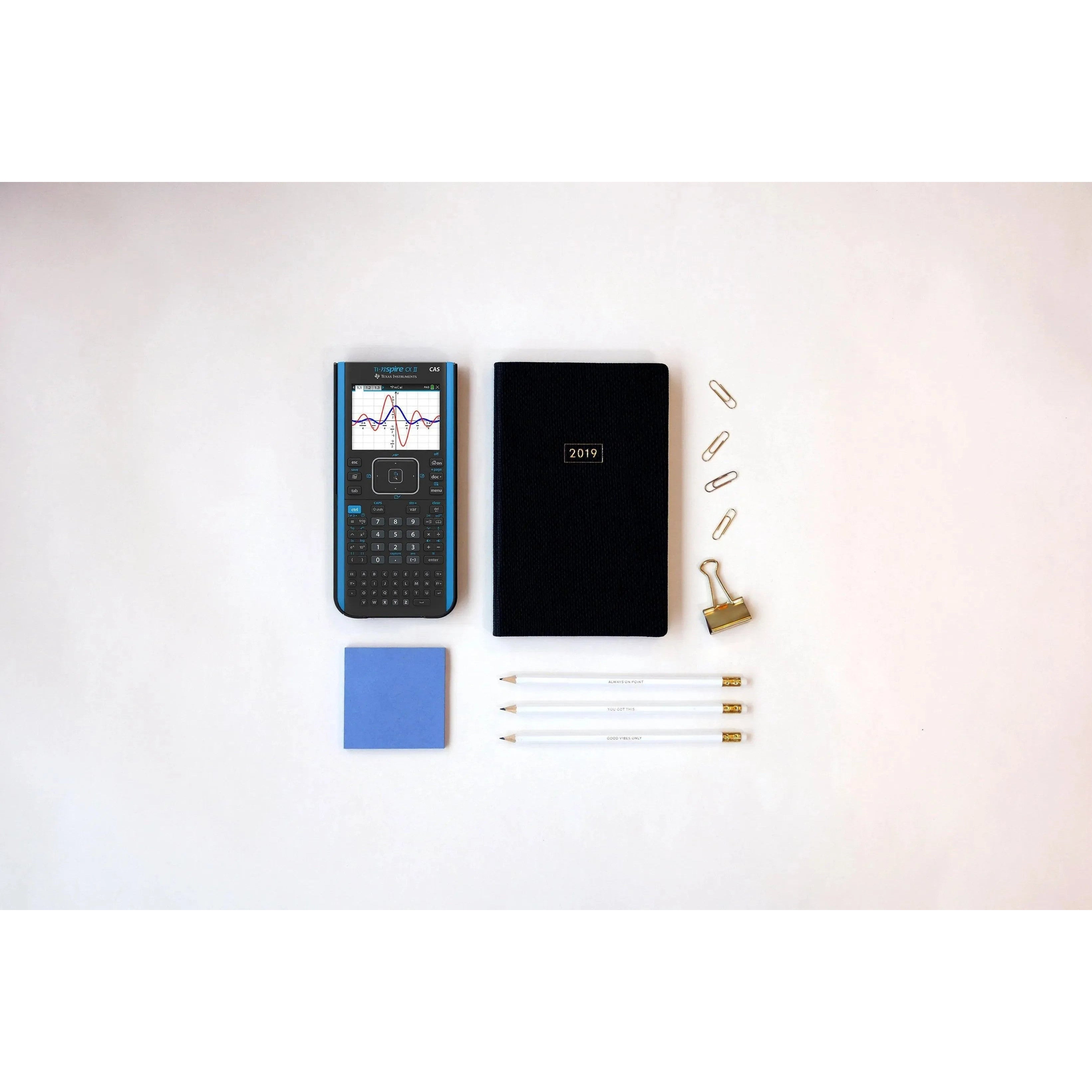 TI-Nspire CX II CAS graphing calculator with notebook, pencils, and office supplies on desk